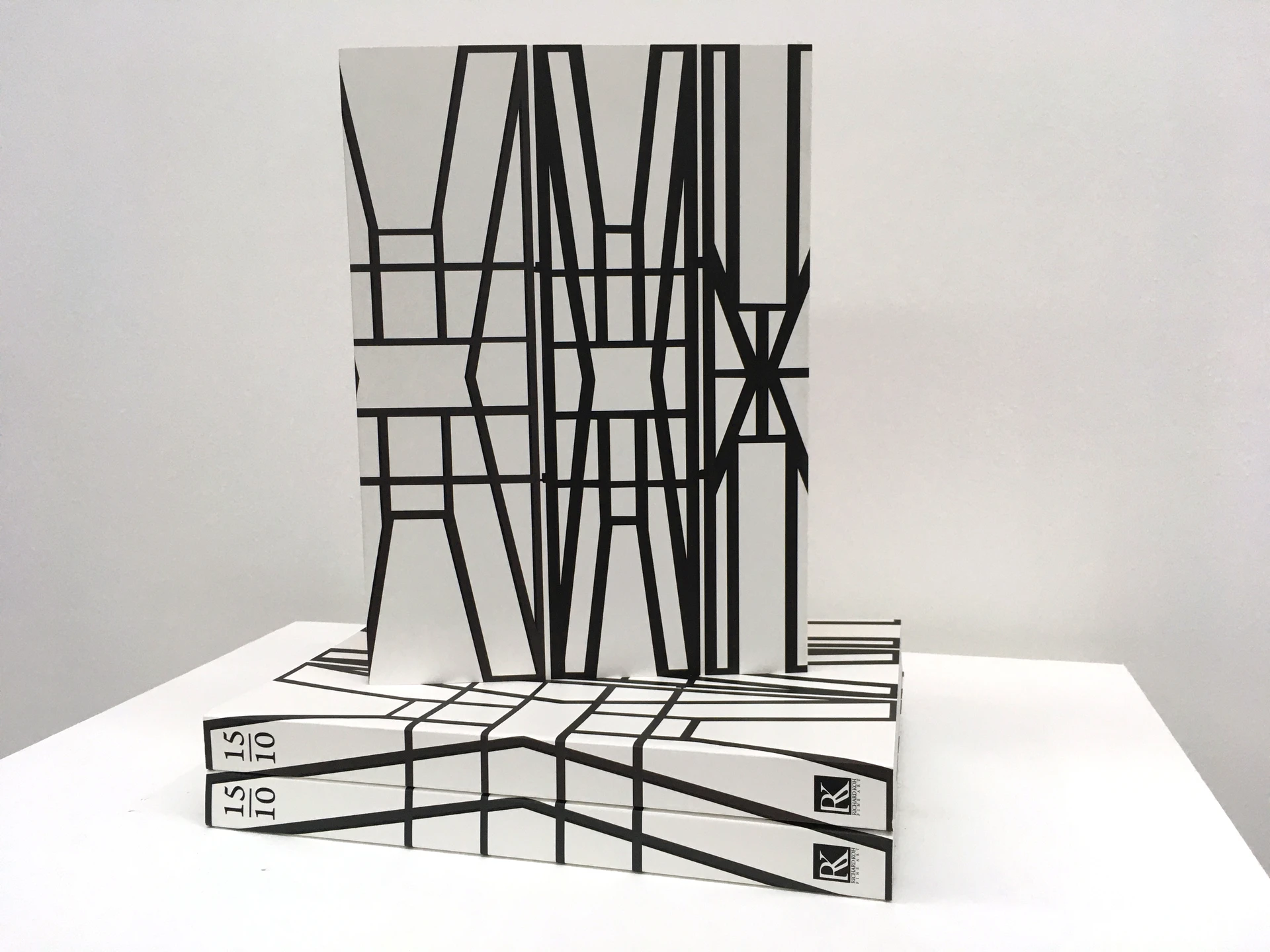 Printed copies of the gallery almanac stacked on a white plinth